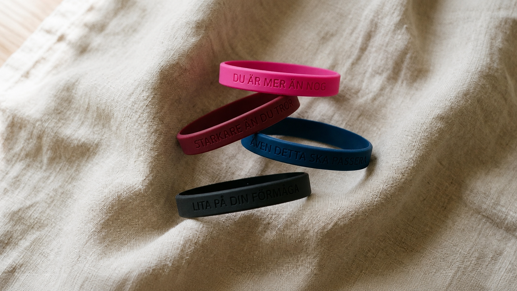 Fyra silikonarmband i rosa, mörkröd, mörkblå och svart